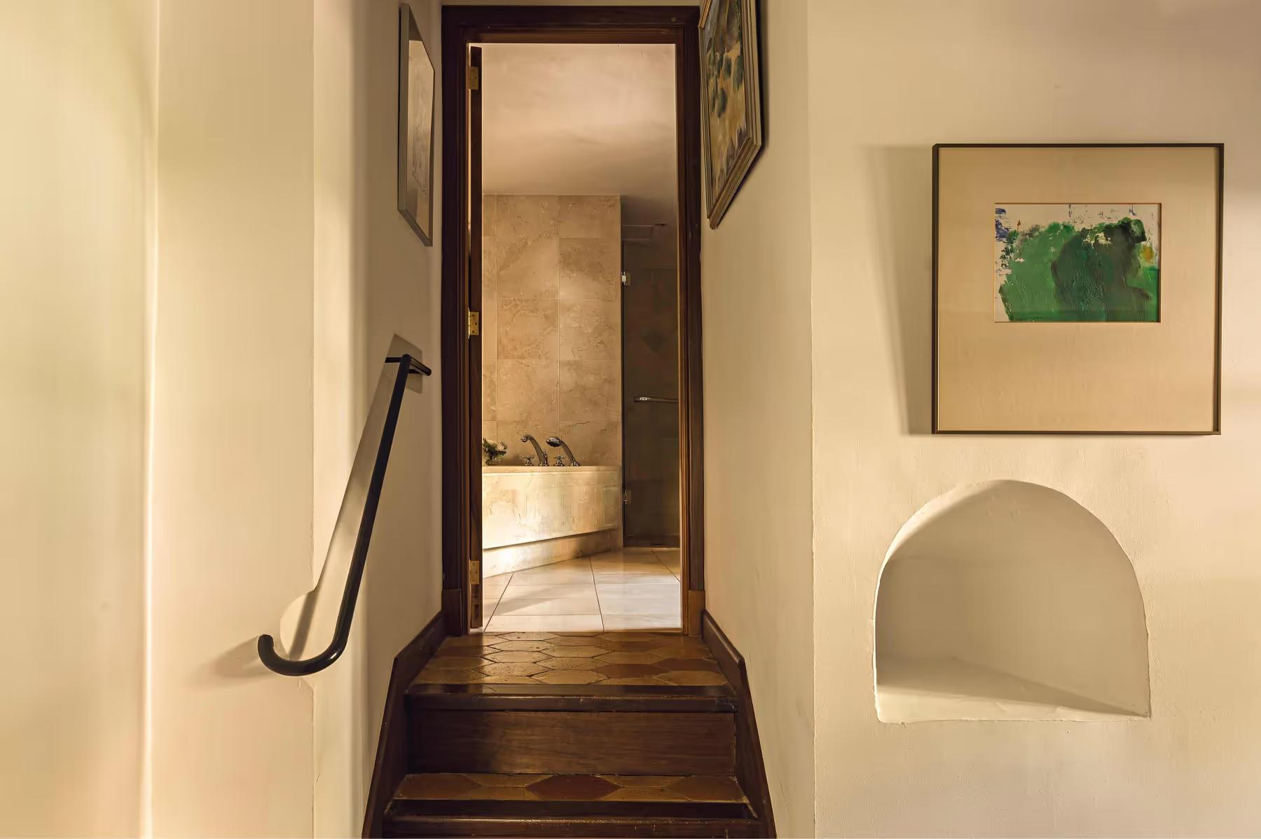 Staircase with dark wooden steps leading upward past a framed painting and archway doorway