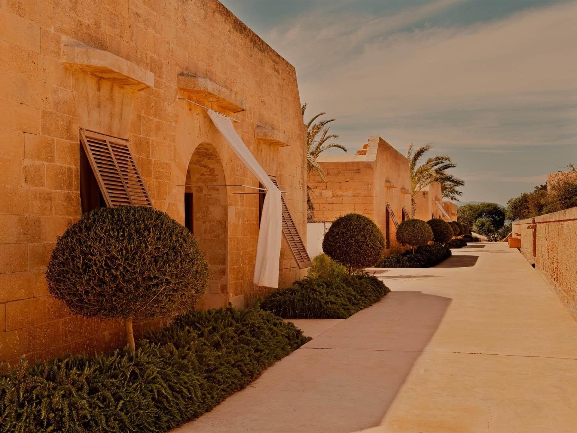 Cap Rocat: a fortification walkway lined with terracotta walls, topiary, and golden hour light