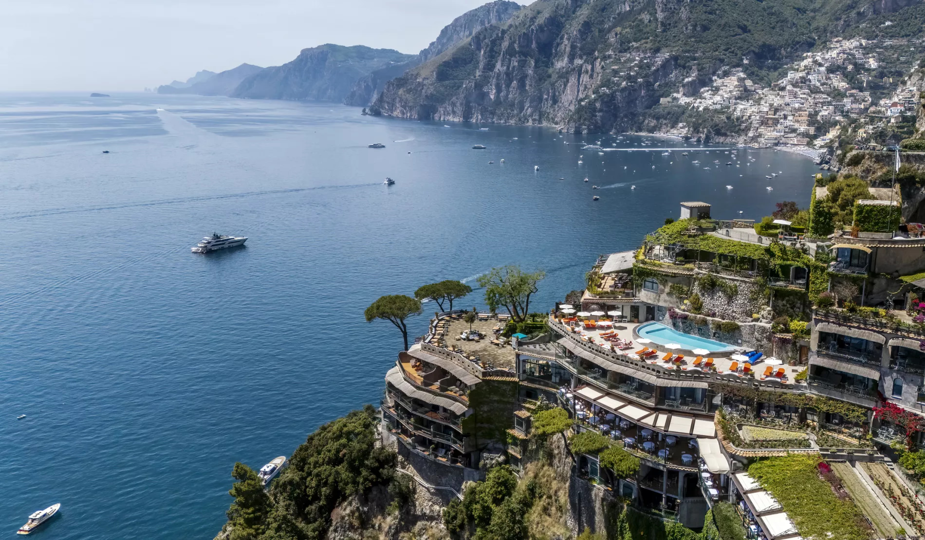 Il San Pietro di Positano: hotel cliffside perch overlooks infinity pool, terraced gardens, turquoise water, anchored yachts, and Positano beyond