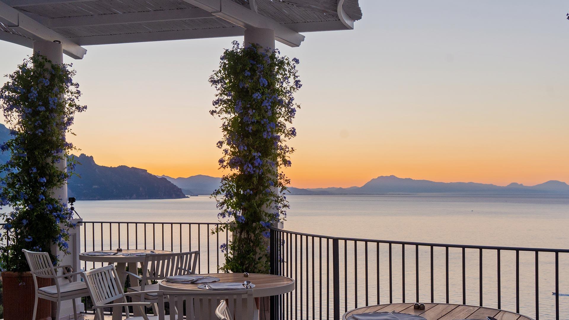Borgo Santandrea: waterfront terrace at sunset with ivy-wrapped columns framing coastal vista