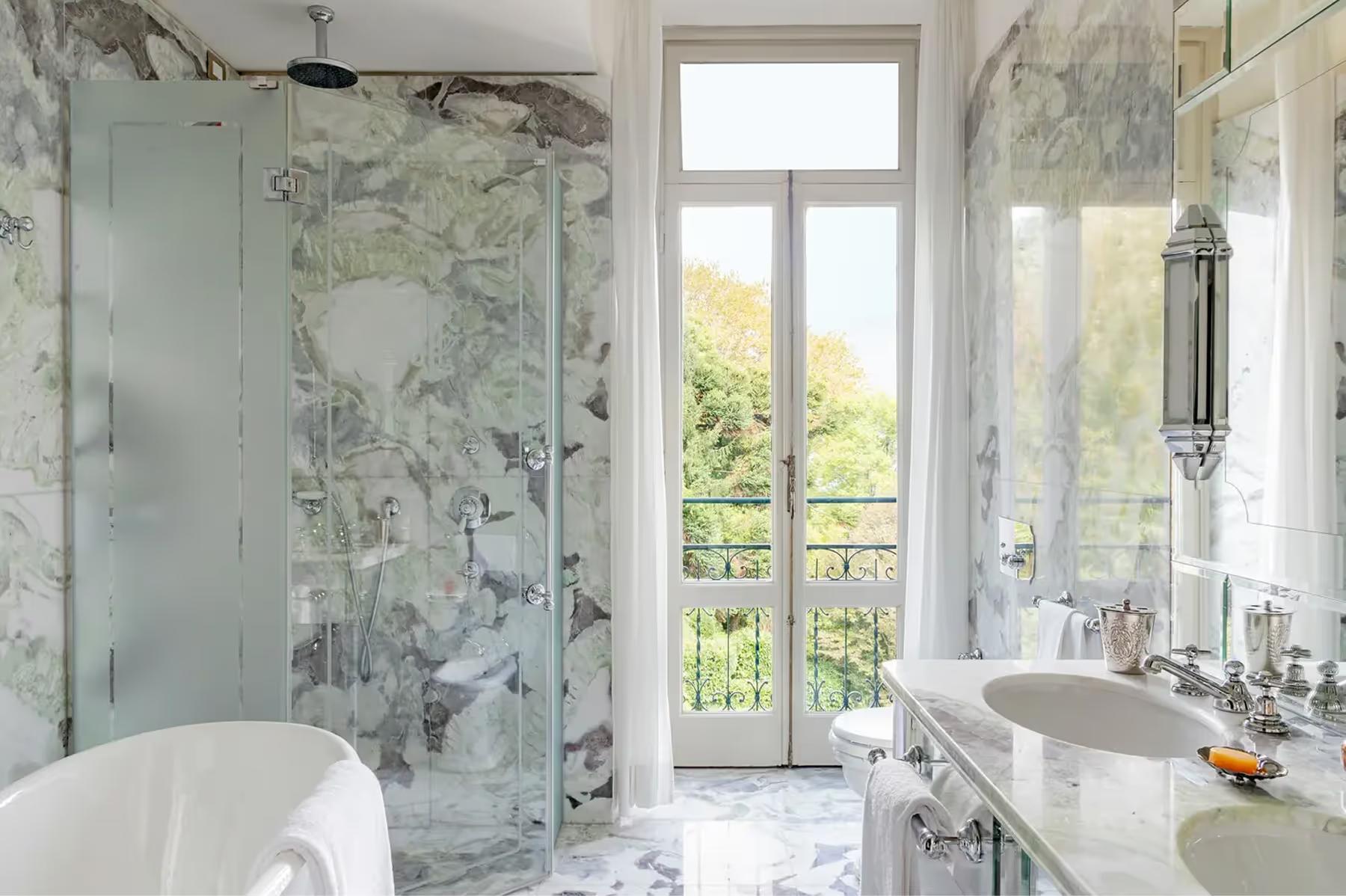Marble bathroom with glass shower enclosure and lake-view doors