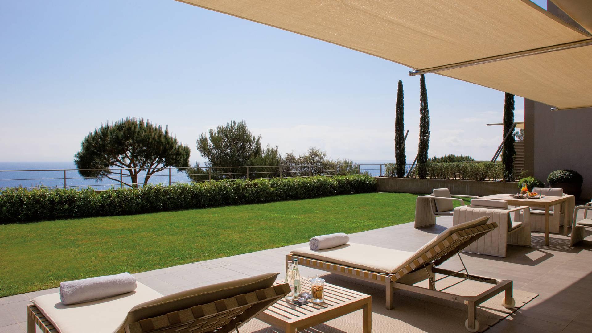 La Réserve Ramatuelle: lawn and sea views from an open terrace with wood furnishings