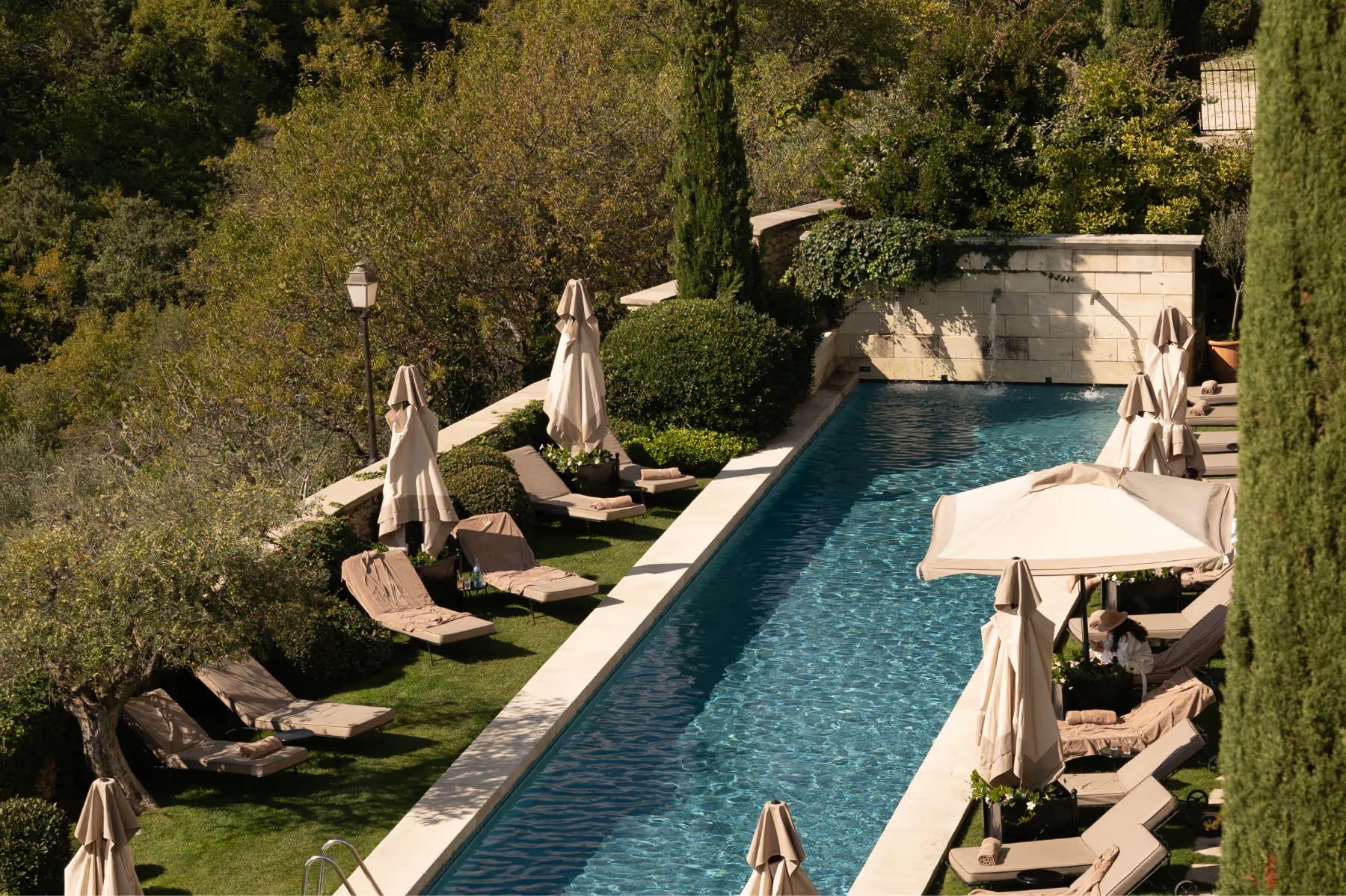 Airelles Gordes, La Bastide: aerial view of rectangular pool surrounded by cypress and manicured lawn