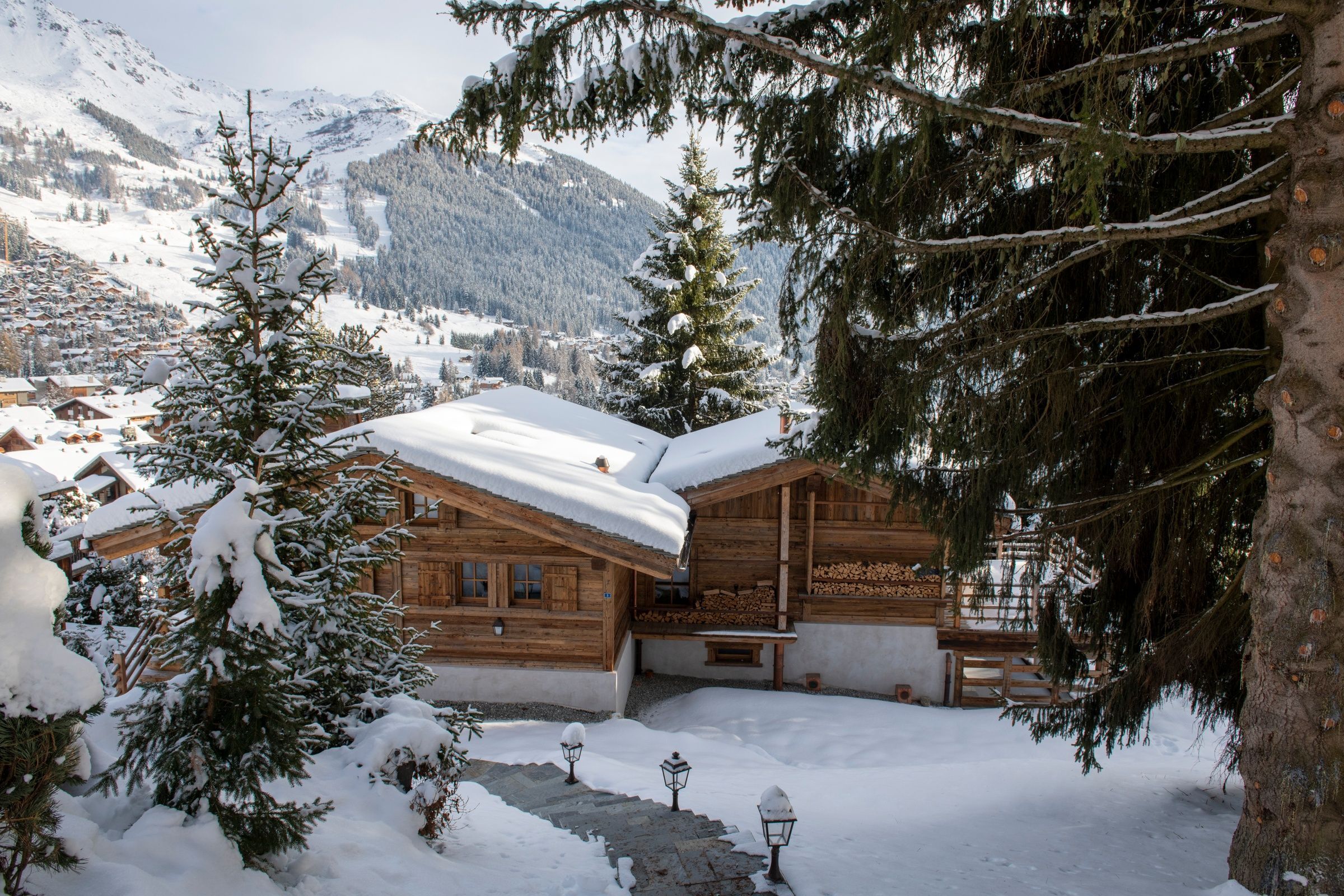 Snow-covered timber chalets in Verbier with forested slopes behind