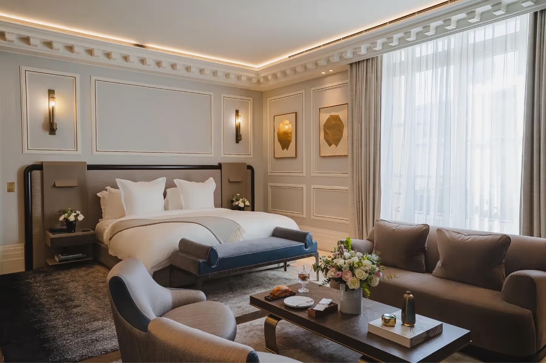 Maison Villeroy: a bedroom with white and gold ceiling details, dark upholstered headboard, and window with sheer curtains