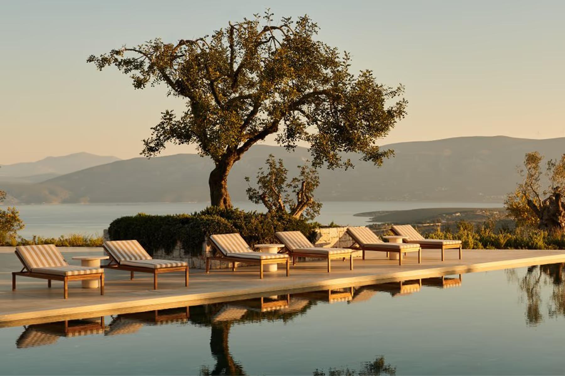 Infinity pool with loungers and sea-view terrace at afternoon light