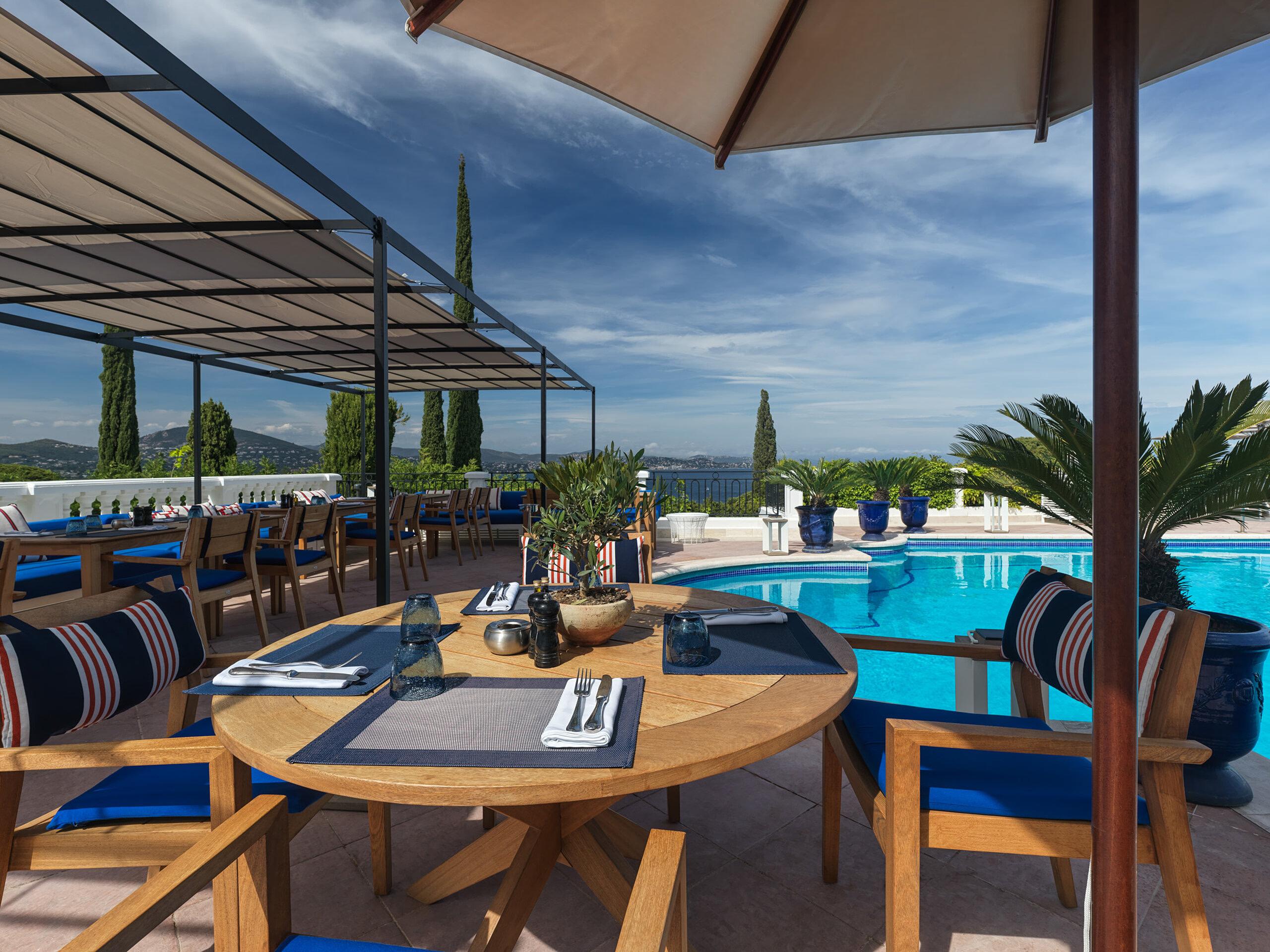Althoff Villa Belrose: waterside terrace dining area with striped cushions overlooking the pools