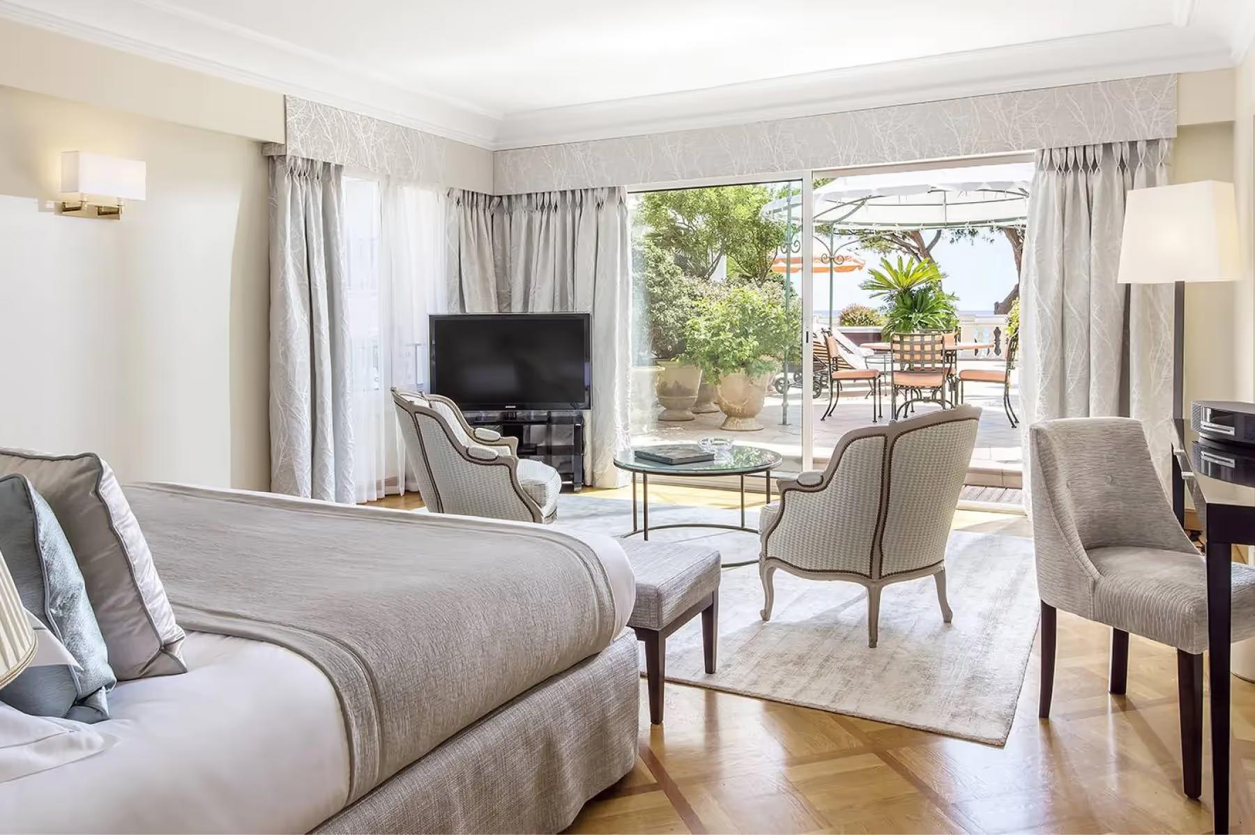 Sunlit room with sofa, floor-to-ceiling windows opening to garden terrace
