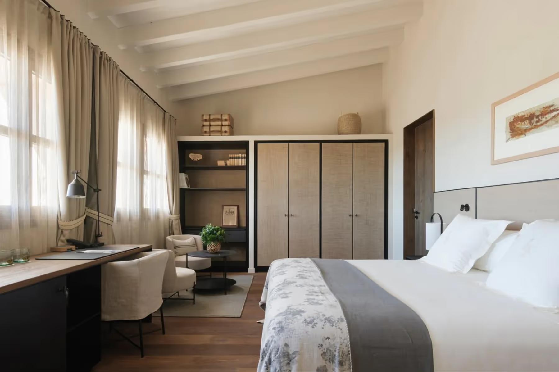 Can Ferrereta: master bedroom with built-in wardrobe, wooden beams, and garden views