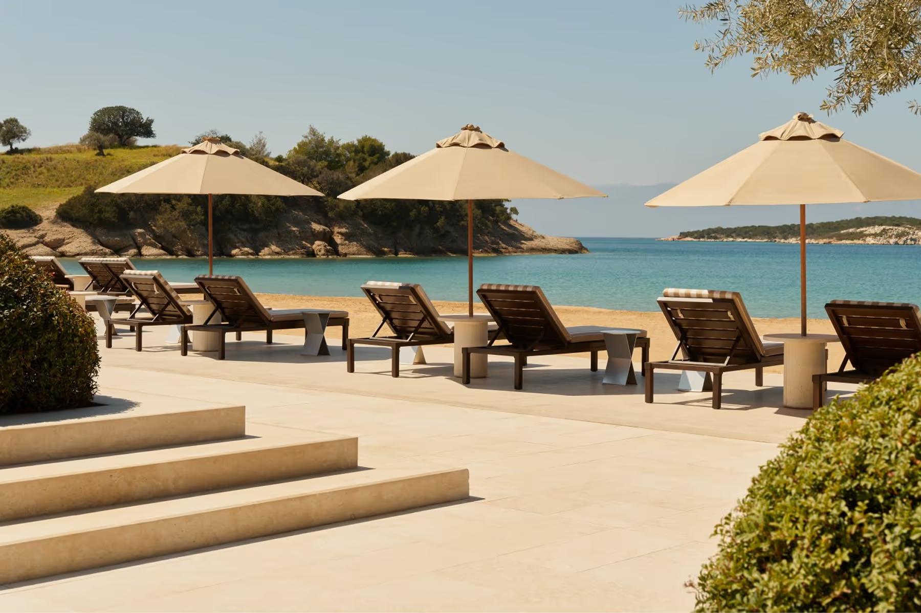 Beach club loungers with umbrellas and calm Mediterranean waters