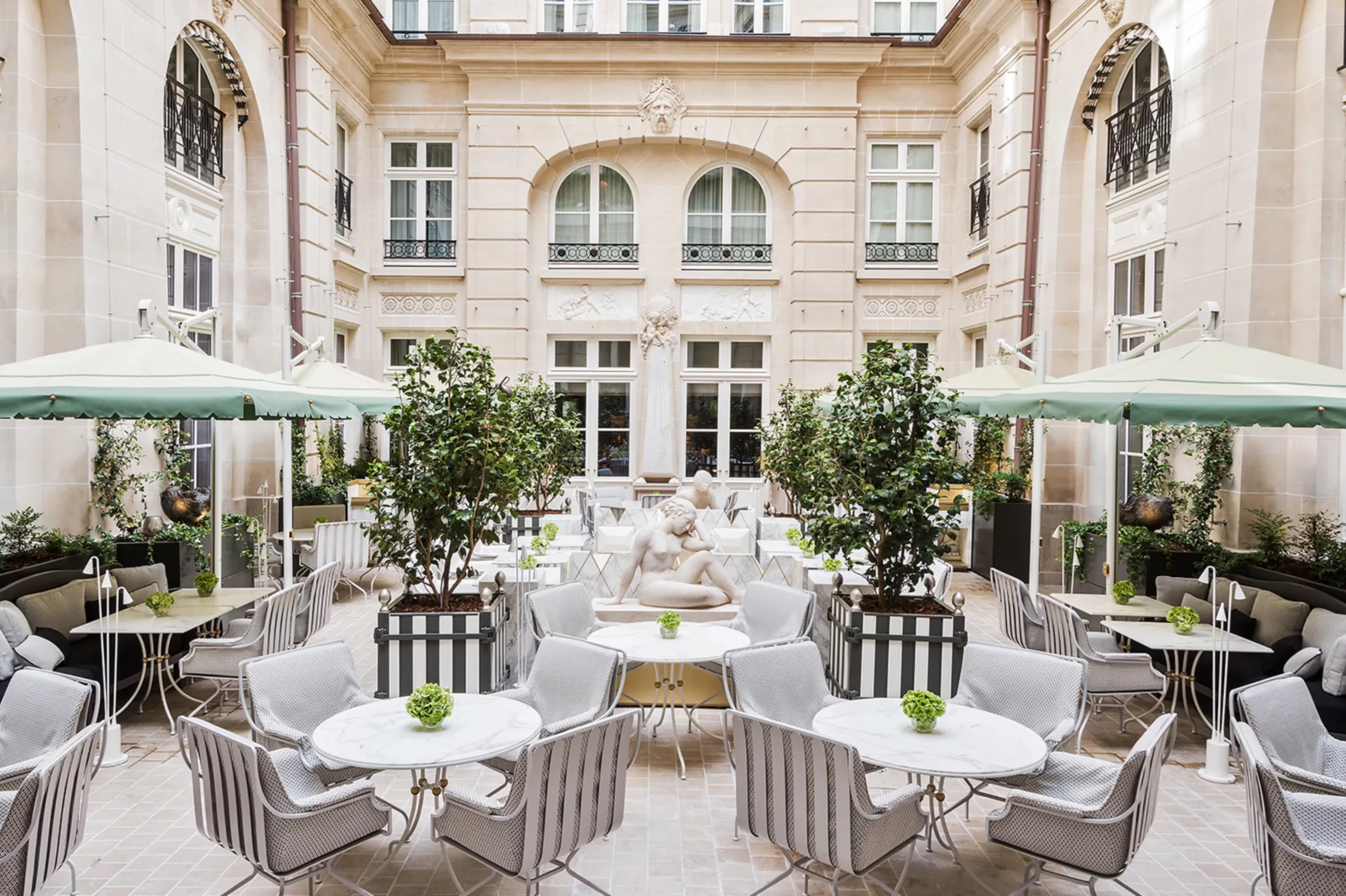Courtyard terrace with white tables and striped chairs overlooking classical architecture