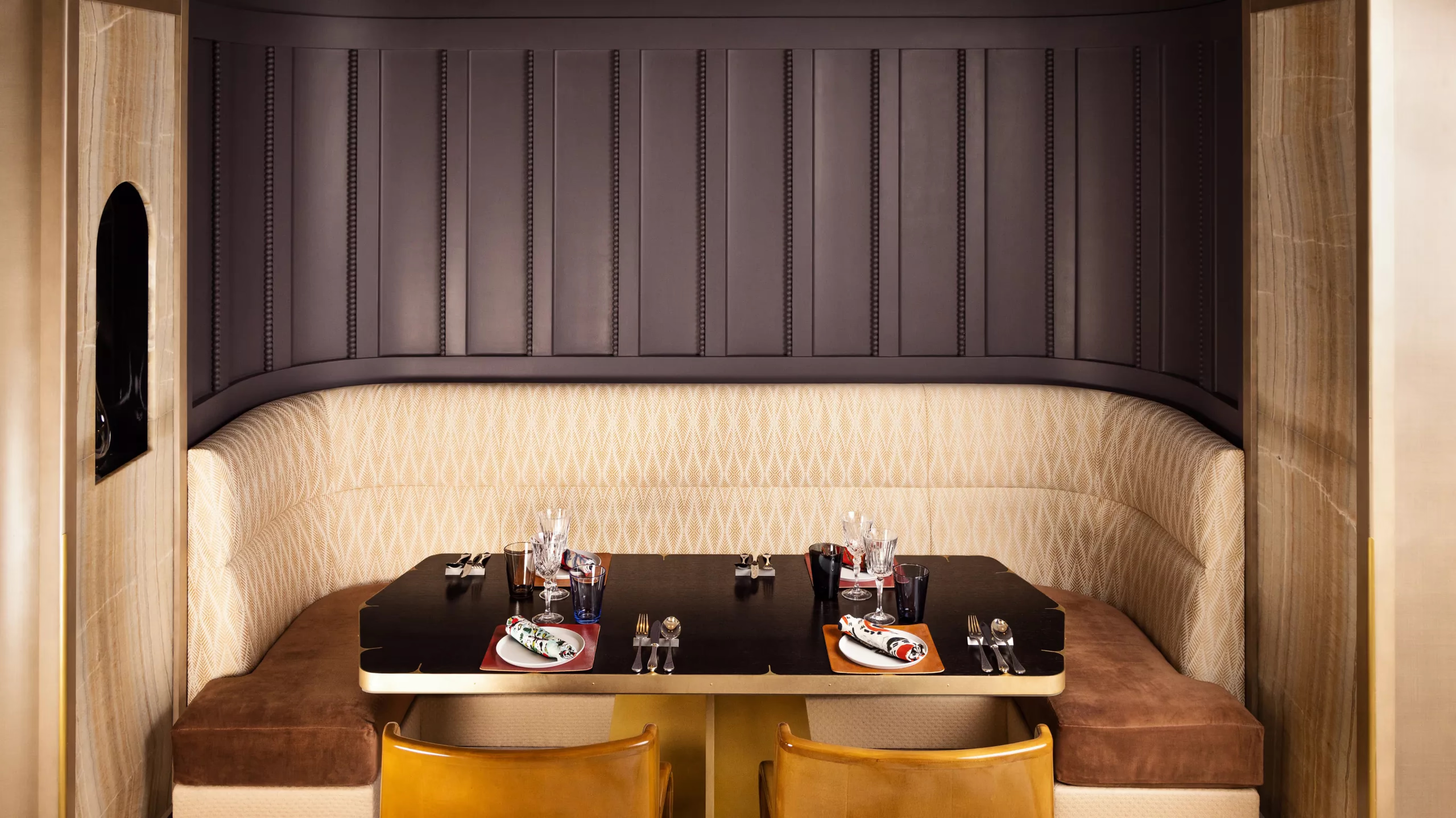 Intimate dining alcove with dark upholstered banquette and copper accents