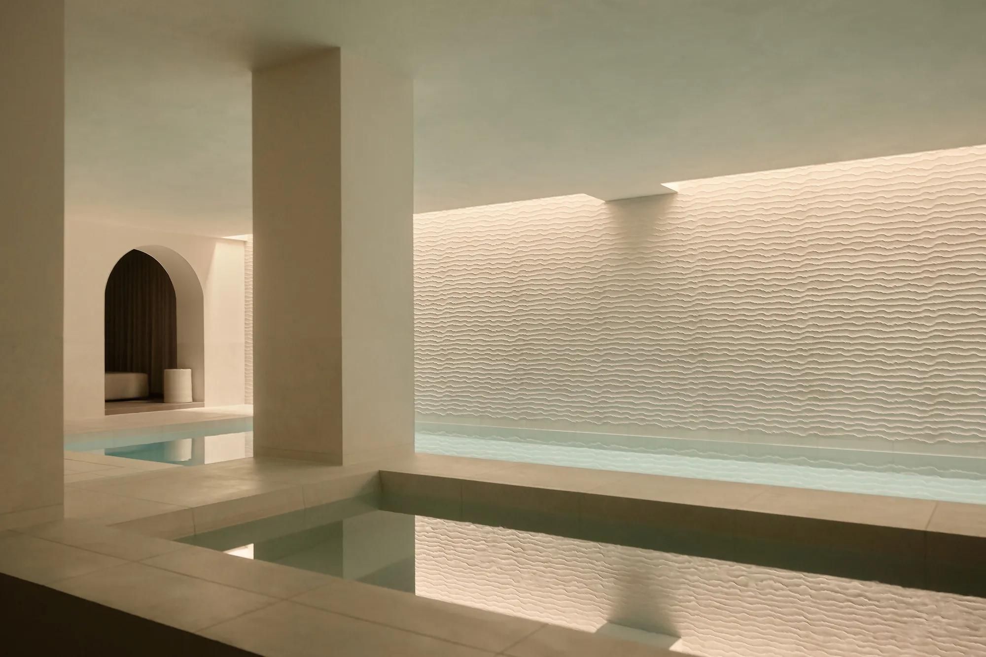 Rosewood Amsterdam: the indoor pool at Asaya spa with a textured white wall and an arched alcove