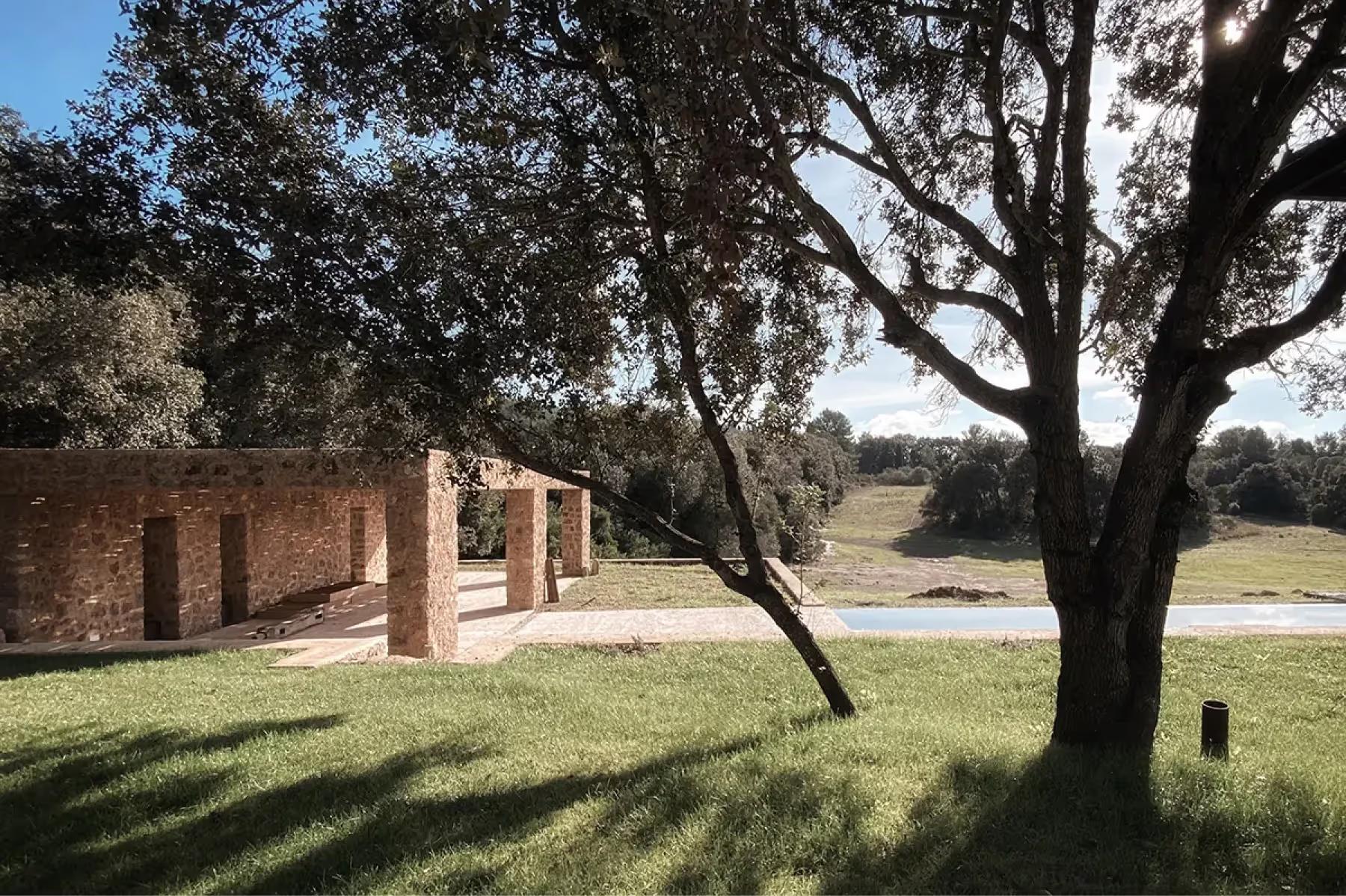 Es Racó d’Artà: stone building with rounded archway entrance situated within grassy estate with mature olive trees