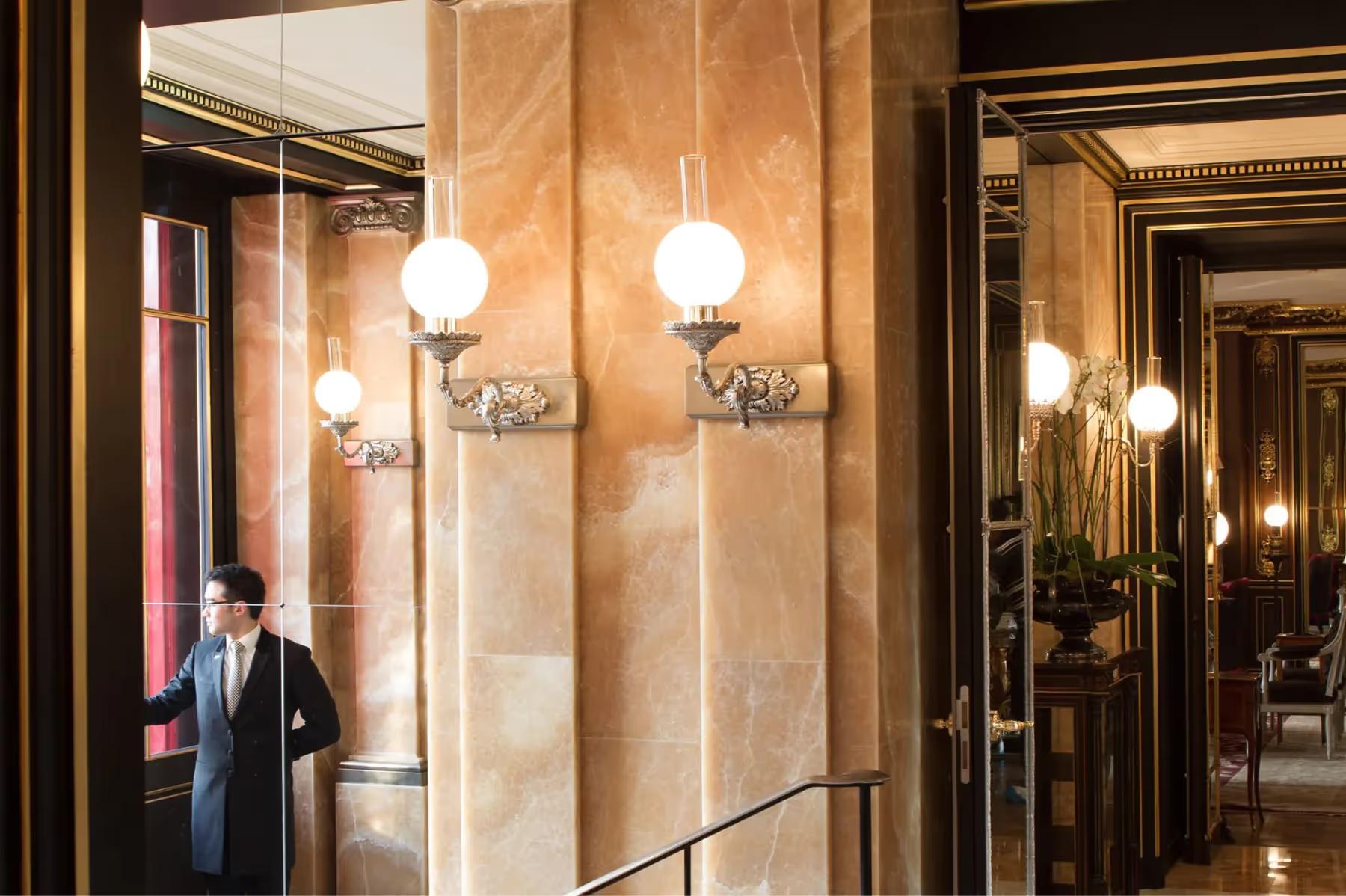 La Réserve Paris: an interior corridor with stone walls and globe pendant lights