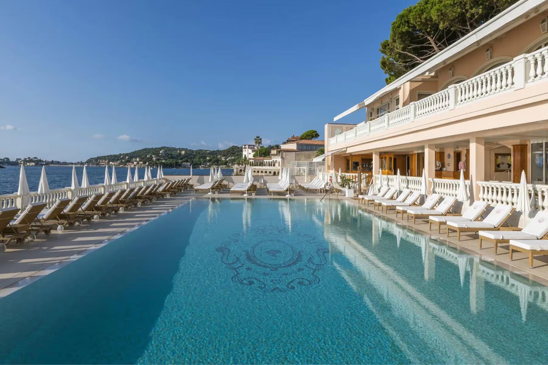 La Réserve de Beaulieu: long pool with deck loungers and Mediterranean shoreline in the distance