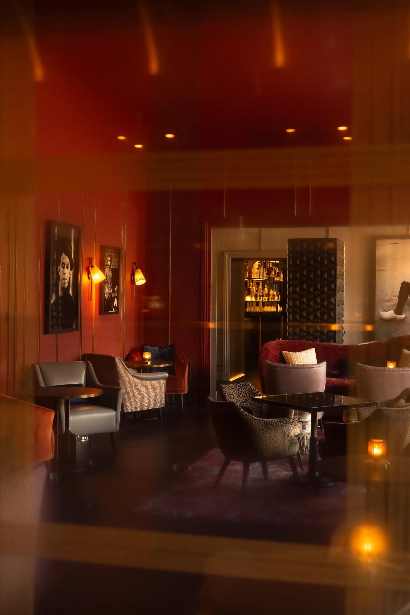 Rosewood Amsterdam: the Advocatuur lounge with red walls, framed portraits, and low armchairs
