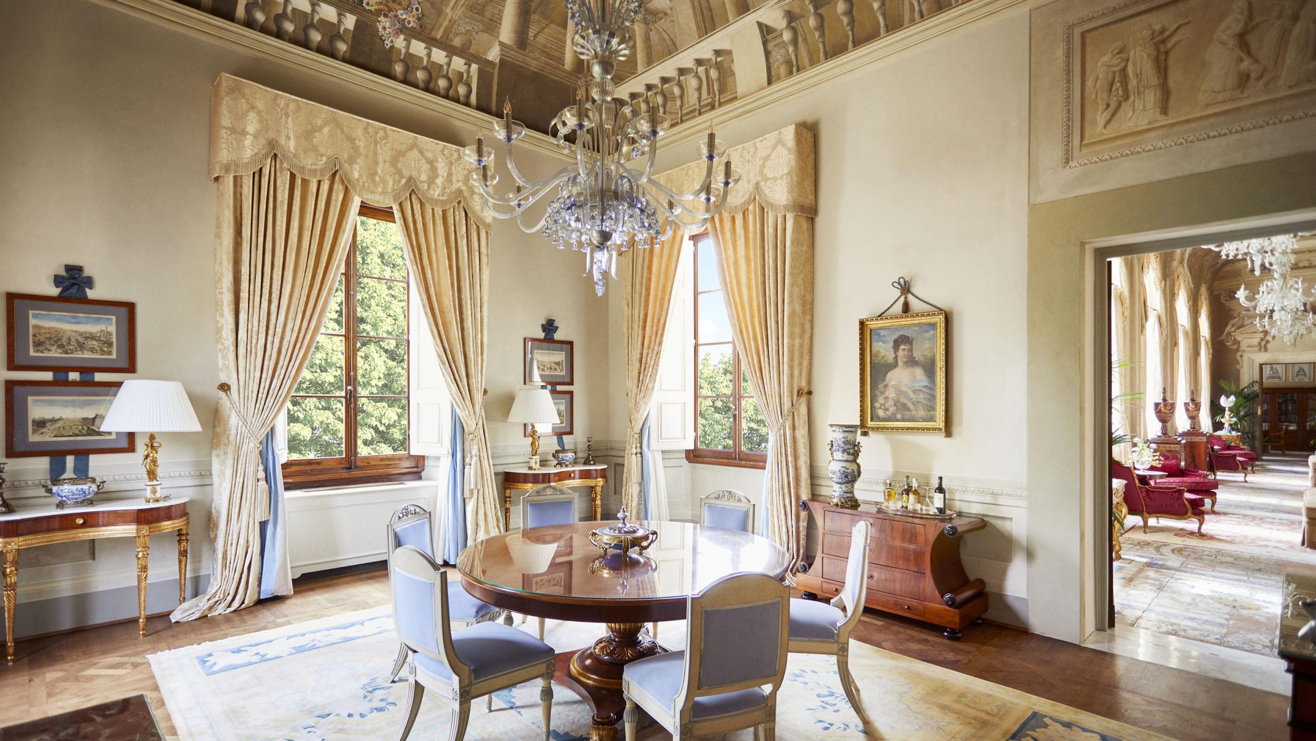 Four Seasons Hotel Firenze: high-ceilinged sitting room with tall windows, yellow silk damask drapery, and classical furnishings