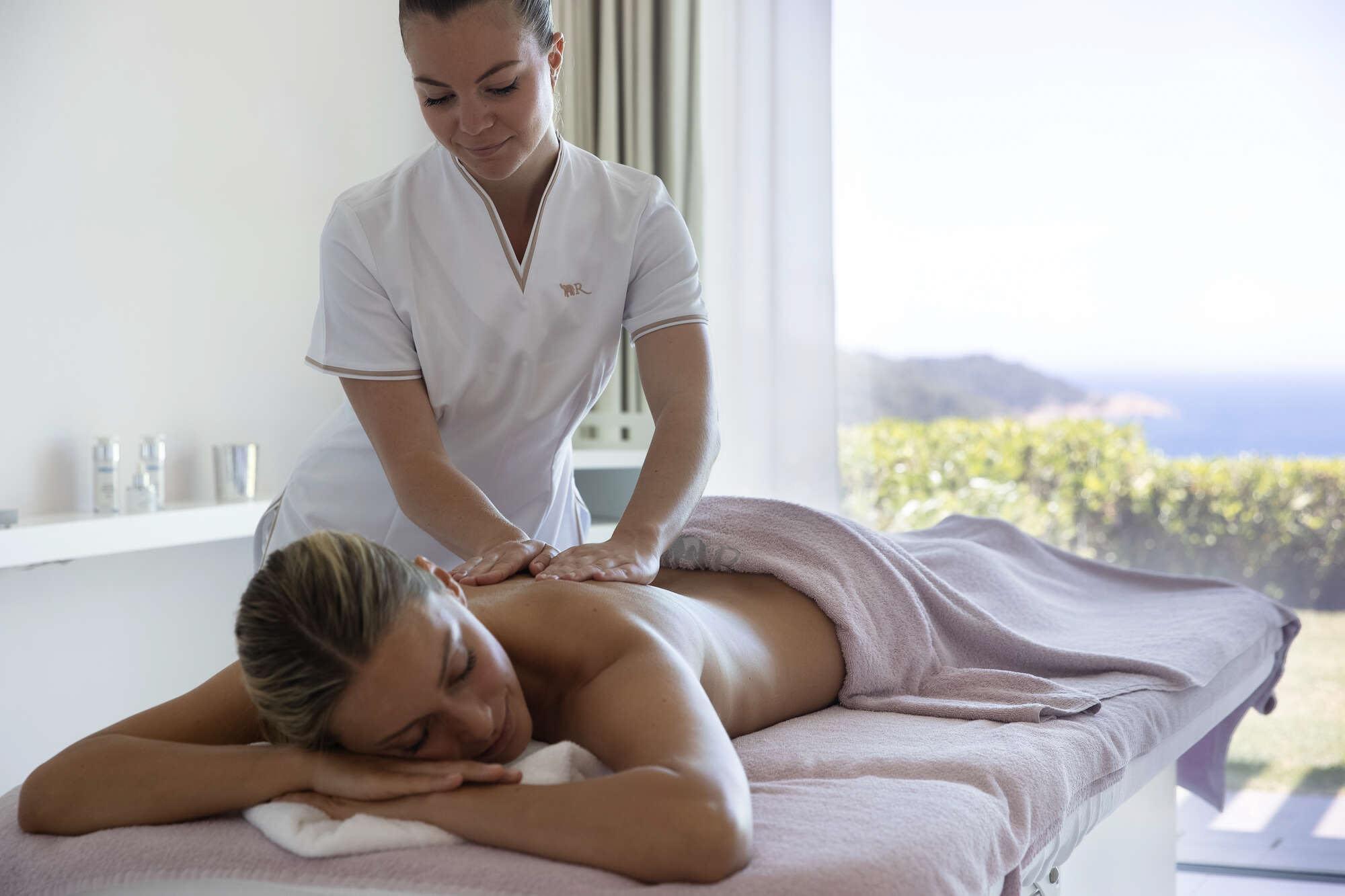 Spa therapist performing massage on guest overlooking the sea