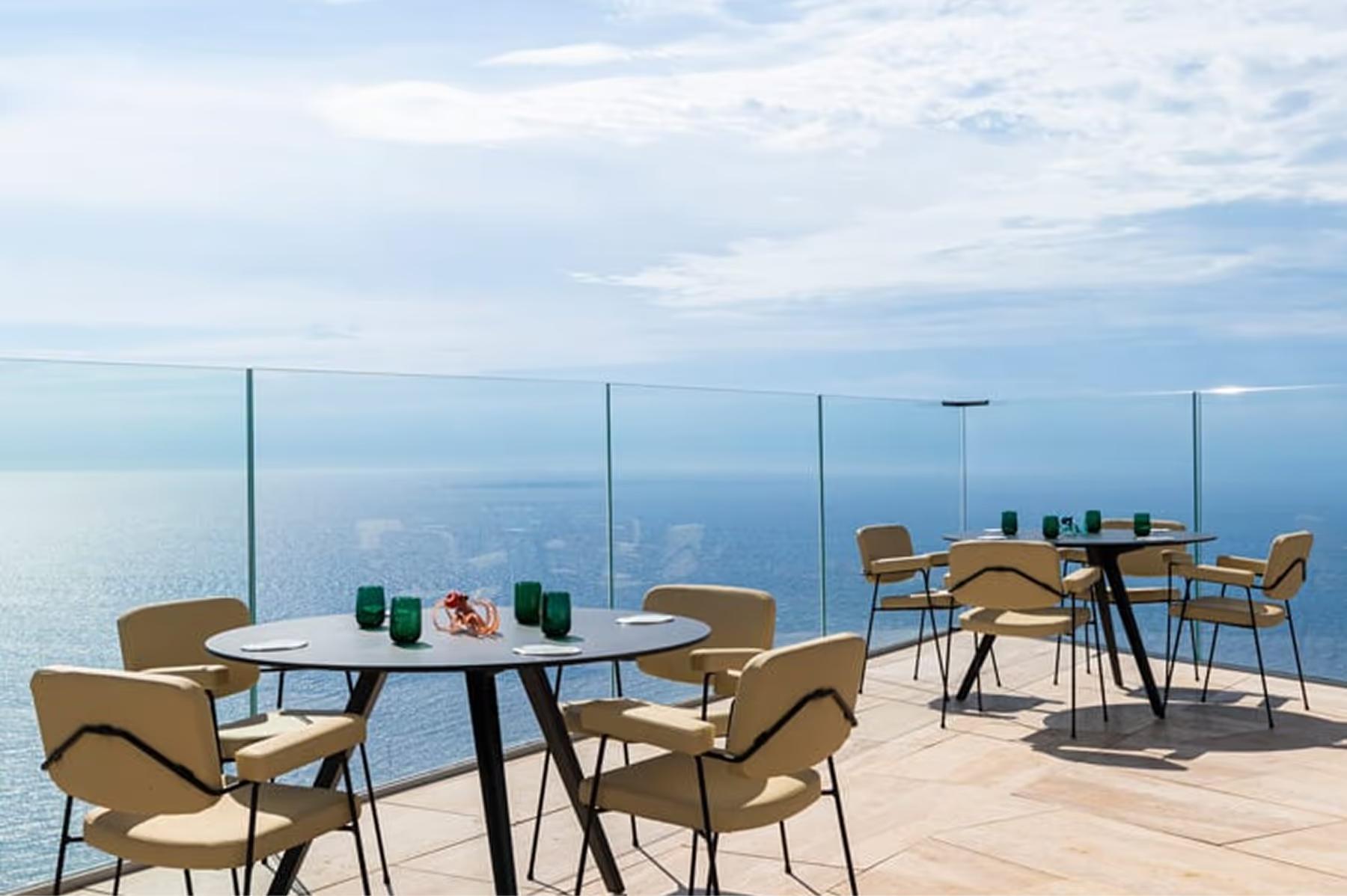 Maybourne Riviera: outdoor dining with dark blue chairs overlooking the coast