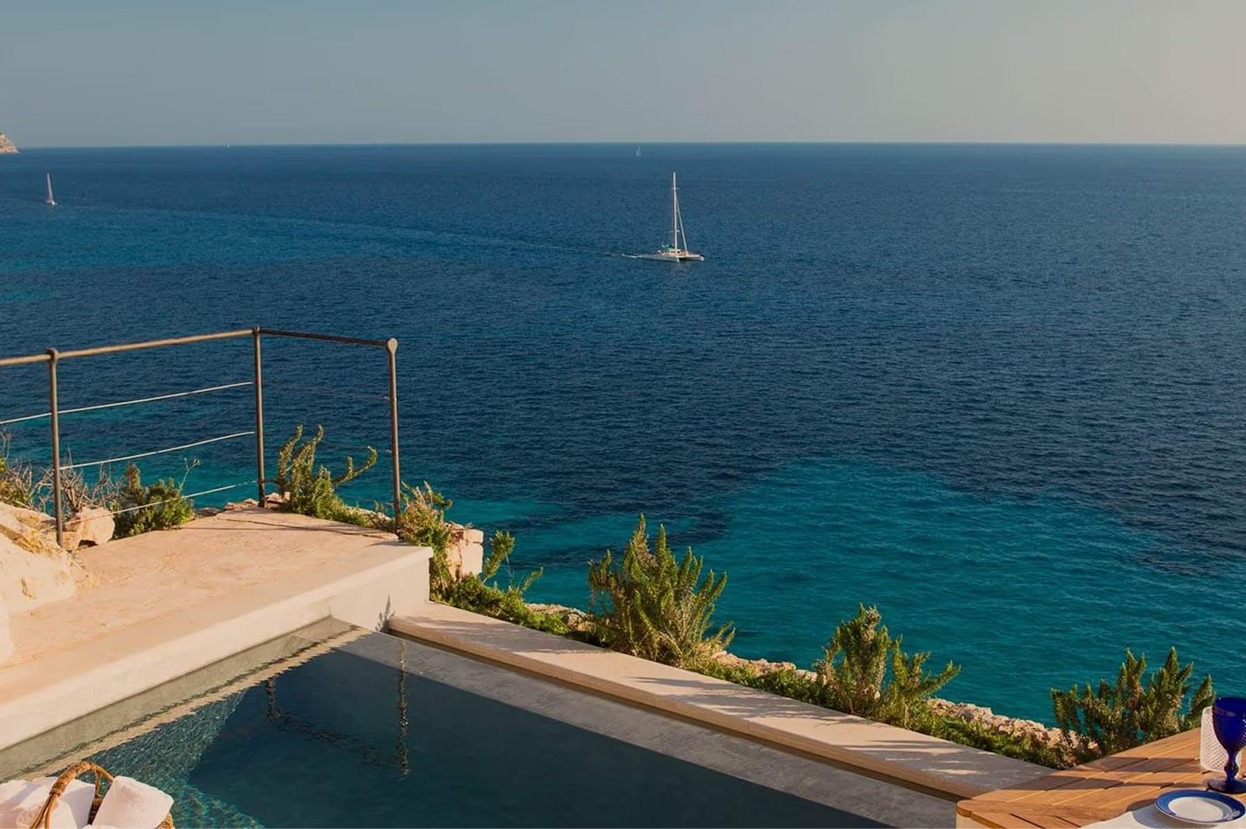 Cap Rocat: a covered deck with reclined loungers and panoramic bay views at sunset