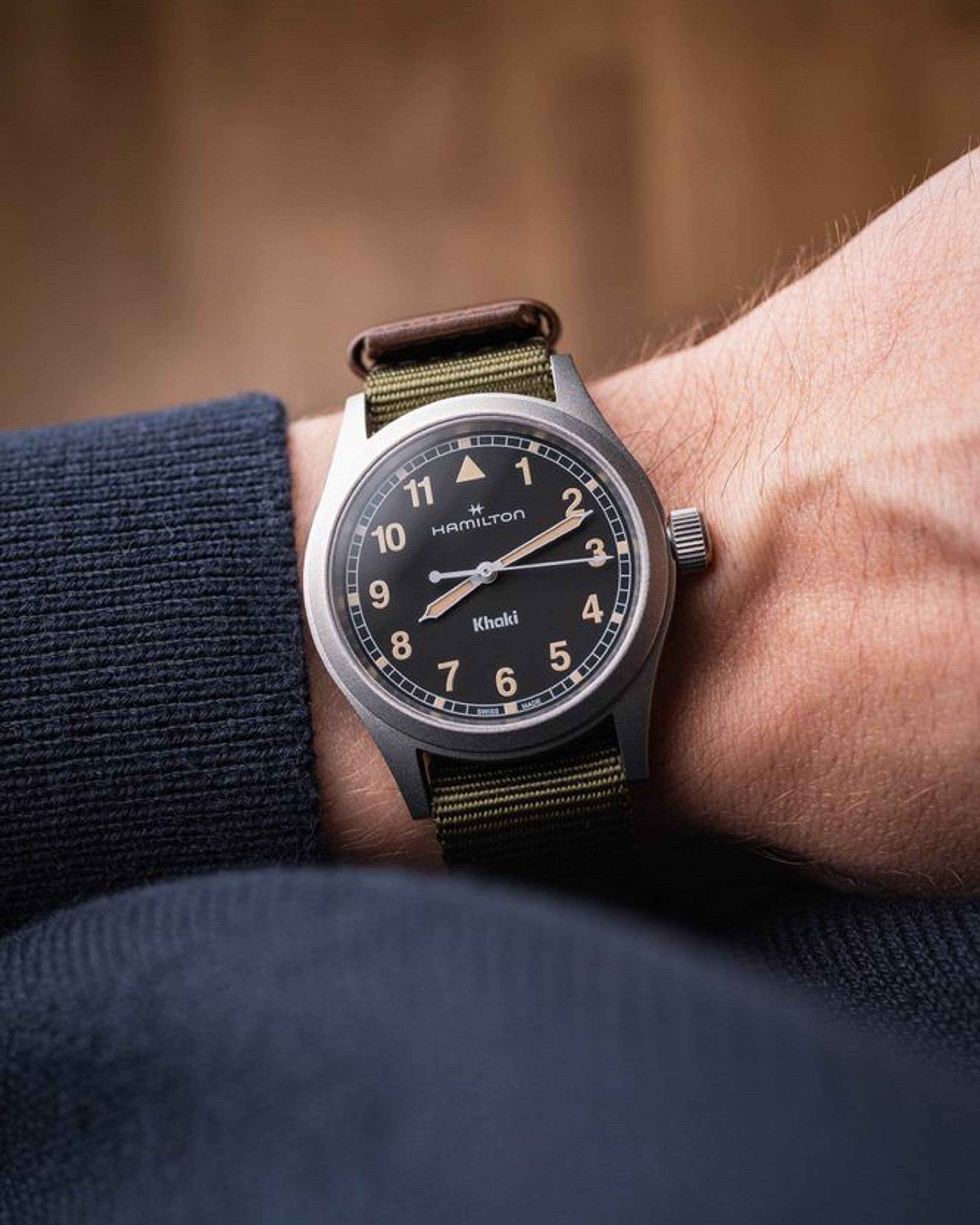 Hamilton Khaki Field Quartz H69401930 on the wrist: black dial with beige vintage-style numerals, green textile NATO strap with a brown leather loop