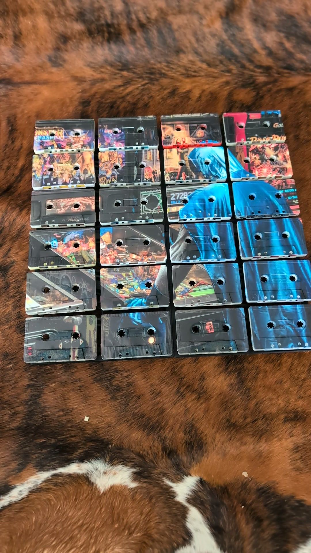 Twenty-four vintage cassette faces arranged in a four-by-six grid and UV printed with a blue figure and colourful collage artwork