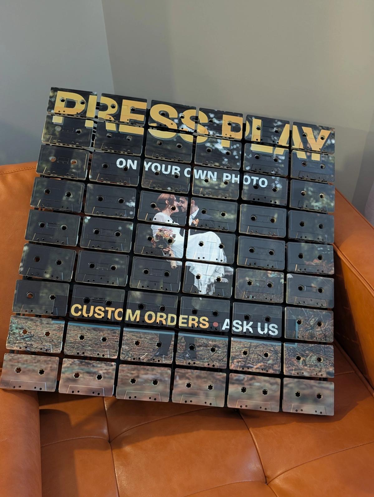 Close view of a custom-photo cassette mosaic with a personal subject beneath Press Play lettering