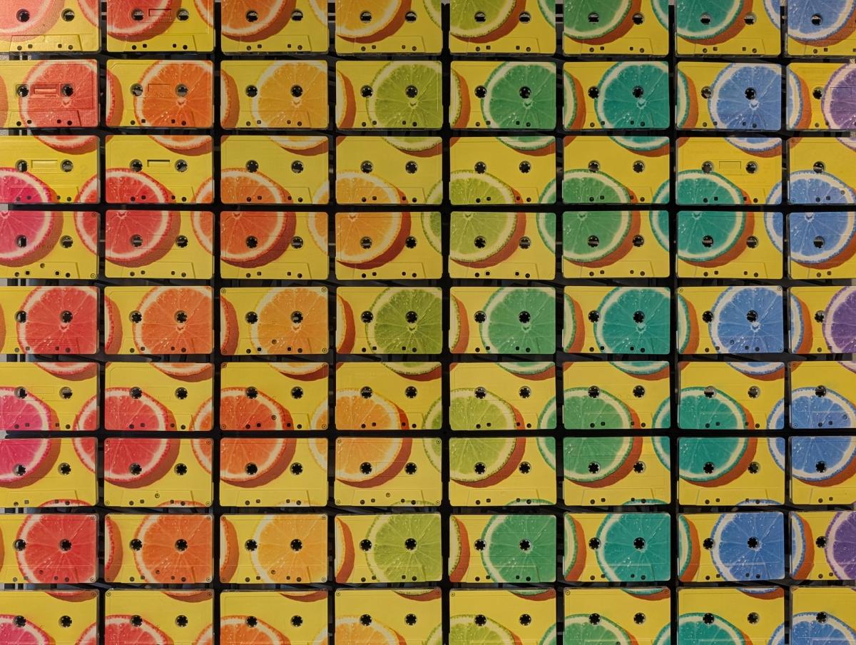 Front view of yellow citrus artwork printed across a grid of real cassette tapes