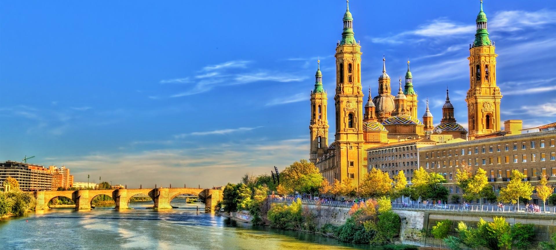 Cathedral-Basilica of Our Lady of the Pillar (Catedral-Basílica de Nuestra Señora del Pilar) and the historic Stone Bridge (Puente de Piedra) along the Ebro River in Zaragoza, Spain. Cathedral-Basilica of Our Lady of the Pillar