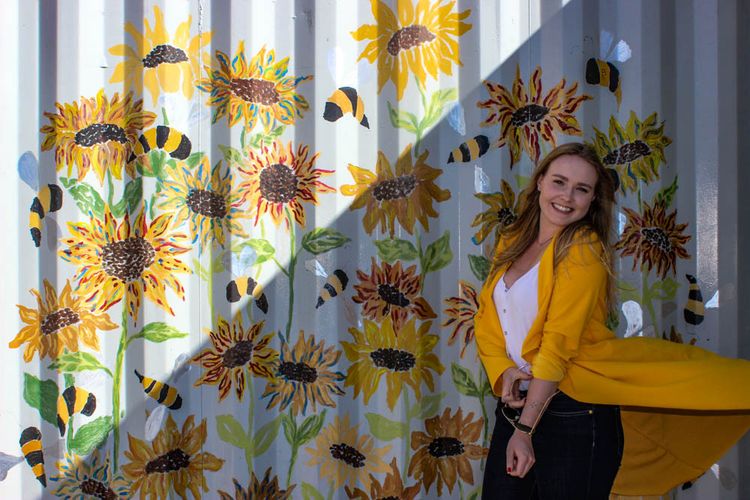 Women in front of floral mural 