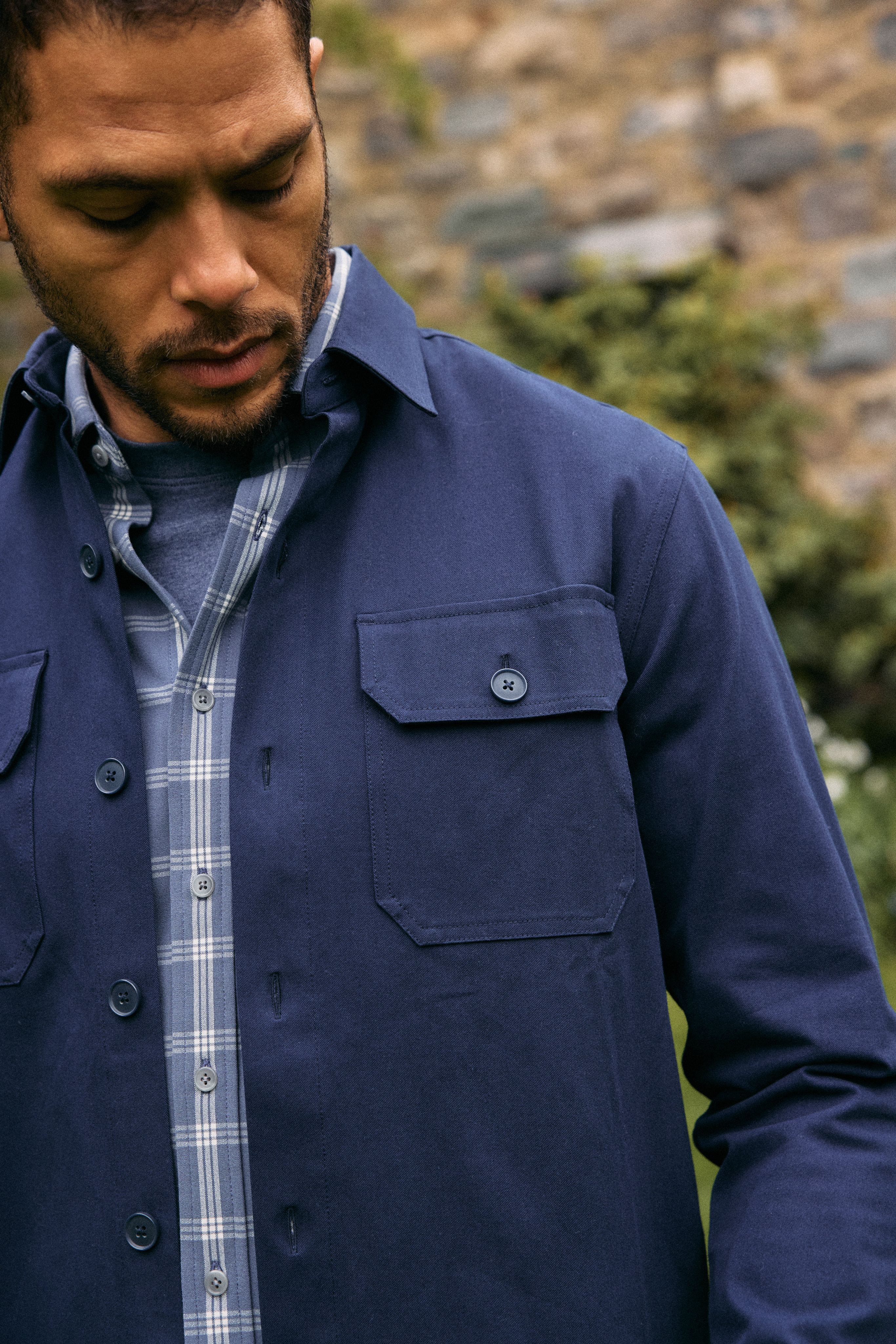 Close-up of a navy shirt jacket layered over a blue plaid shirt