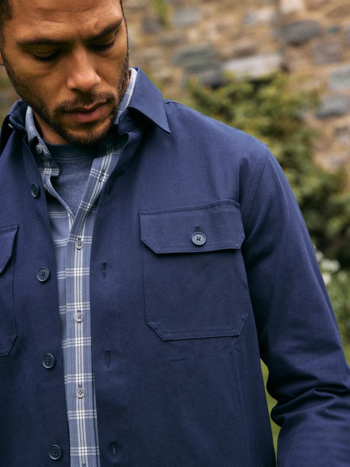 Close-up of a navy shirt jacket layered over a blue plaid shirt