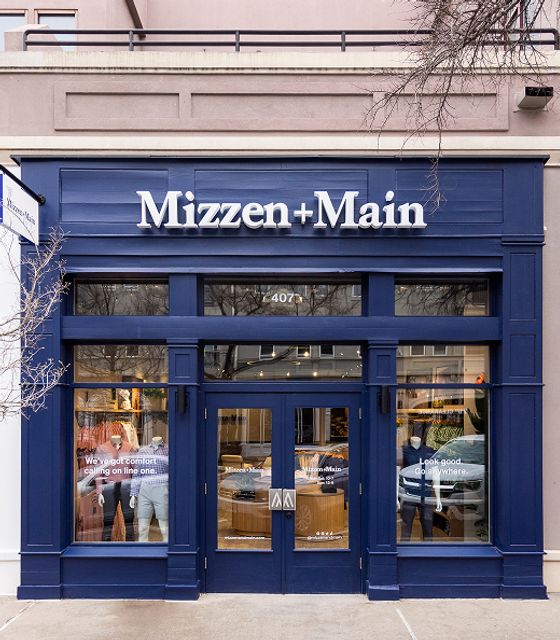 The first Mizzen+Main store: a navy storefront with the brand's name above mannequin-filled display windows.