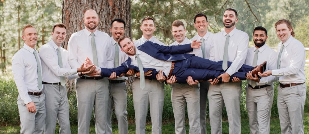 Male wedding party holding the groom as he is laying down