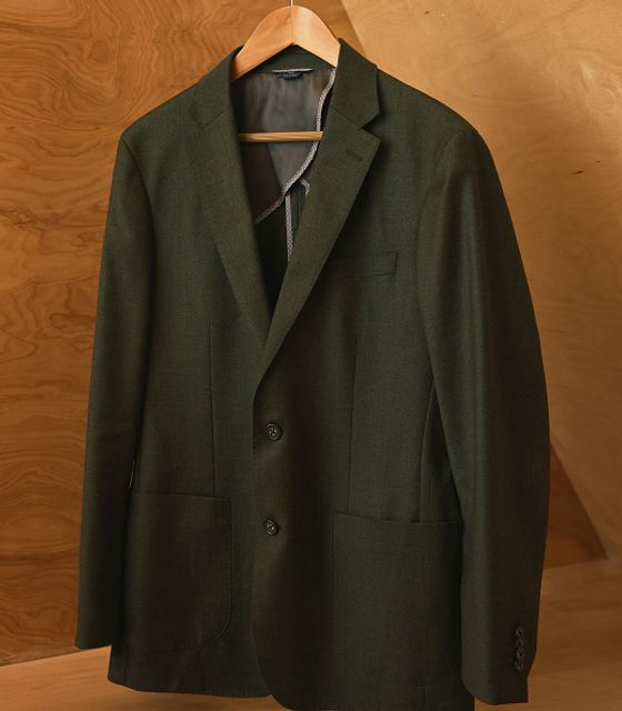 The Lavelle Blazer in dark green on a wooden hanger.