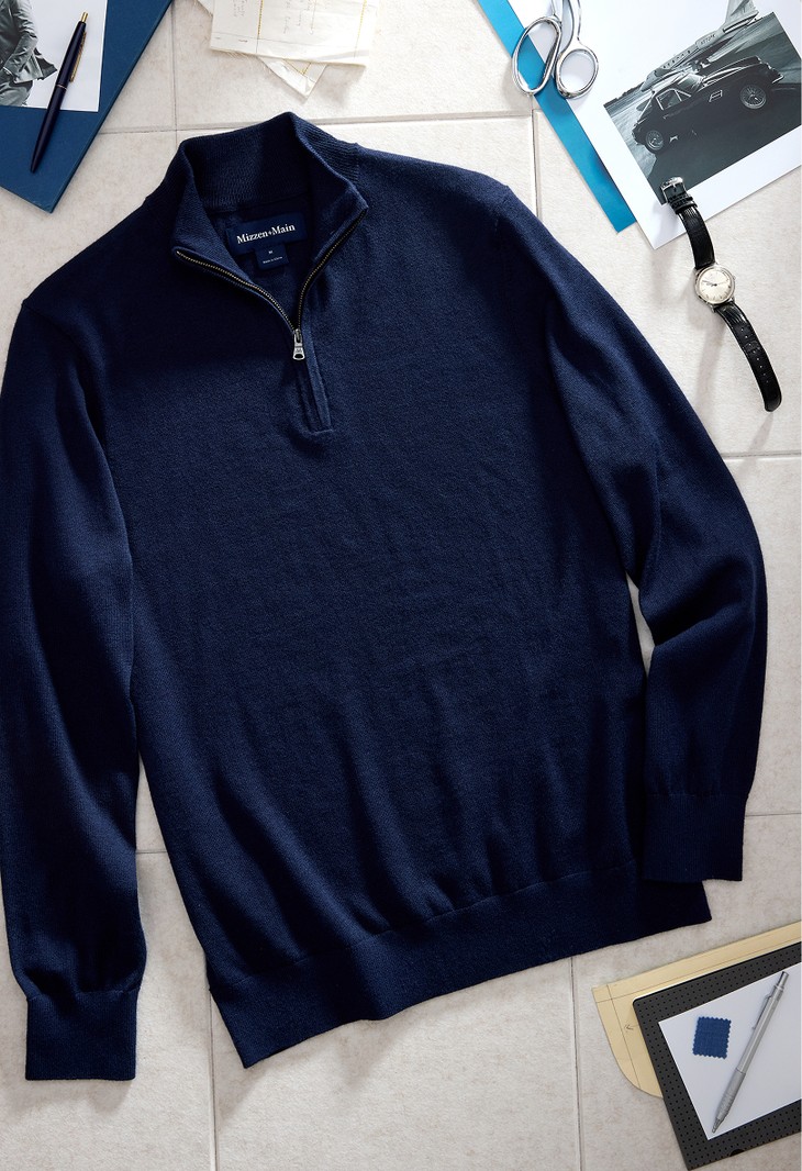 Navy Heritage Quarter Zip Sweater laid flat on a tile surface, next to a wristwatch, scissors and pens.