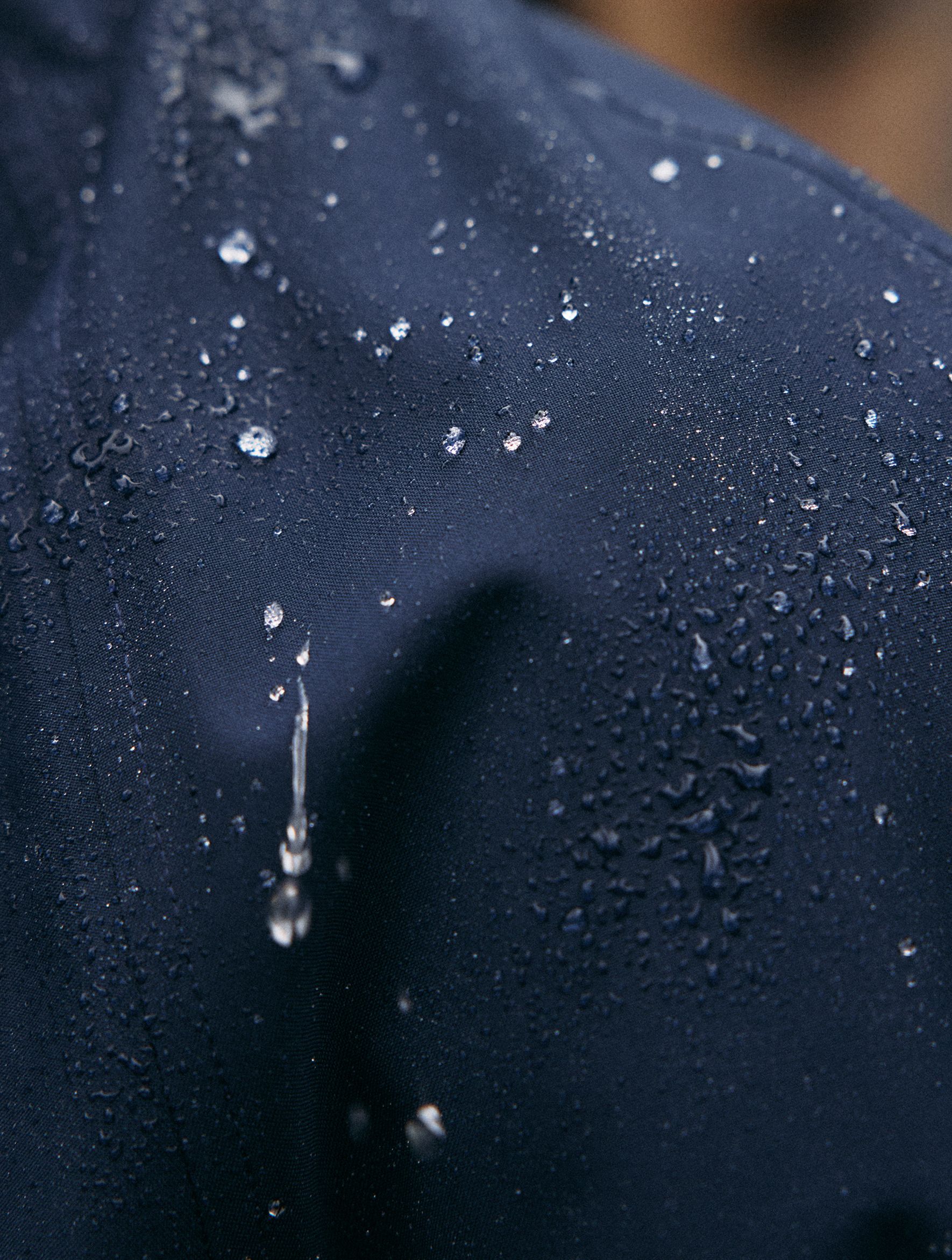 A extreme macro shot showing water droplets beading on water-resistant navy blue fabric.
