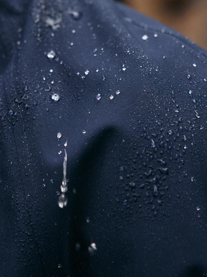 A extreme macro shot showing water droplets beading on water-resistant navy blue fabric.