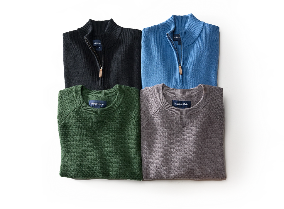 Hillcrest sweaters arranged together: black and blue quarter zips with green and taupe crewnecks