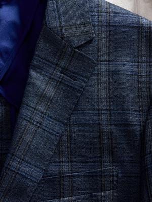 Macro close-up shot focusing on the lapel and textured weave of a dark blue plaid suit jacket.