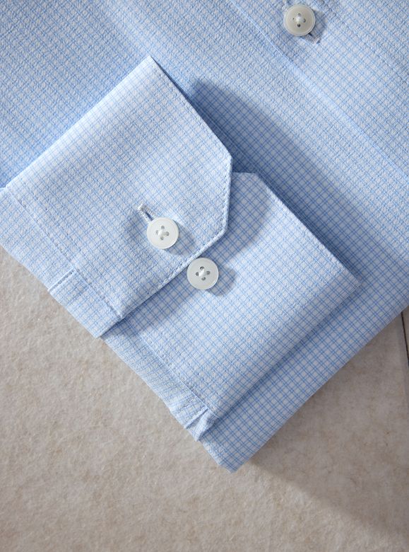 Close-up of a light blue check dress shirt cuff with two white buttons