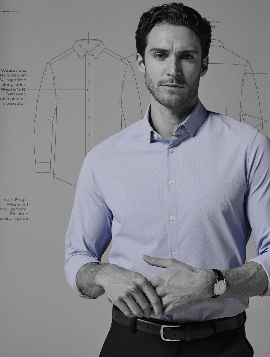 A man in a light-blue dress shirt — the only color in a black-and-white scene — stands in front of technical drawings of a dress shirt's design.