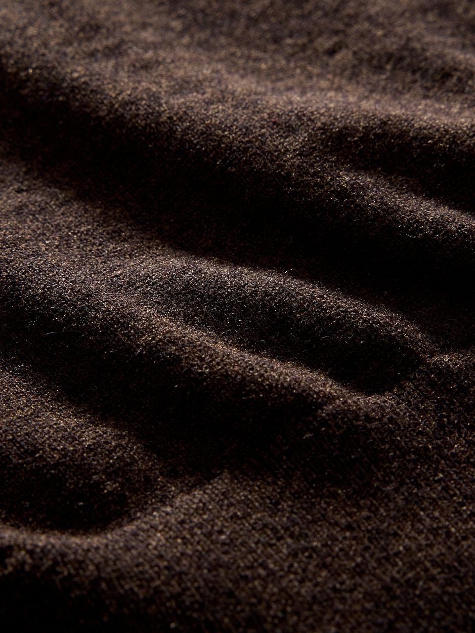 A macro close-up shot of dark brown knit fabric texture with soft lighting.