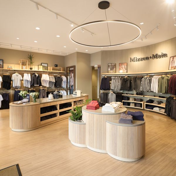 Interior of the Mizzen+Main La Cantera store with wood display tables and racks of shirts