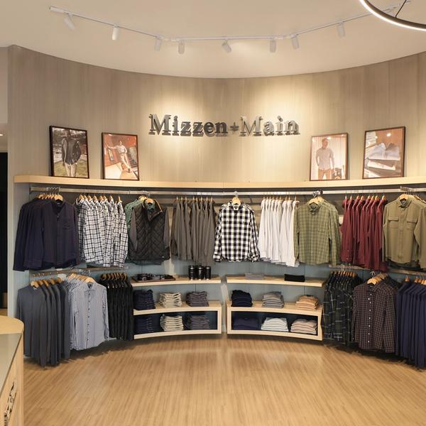 Curved display wall of shirts beneath the Mizzen+Main sign in the La Cantera store