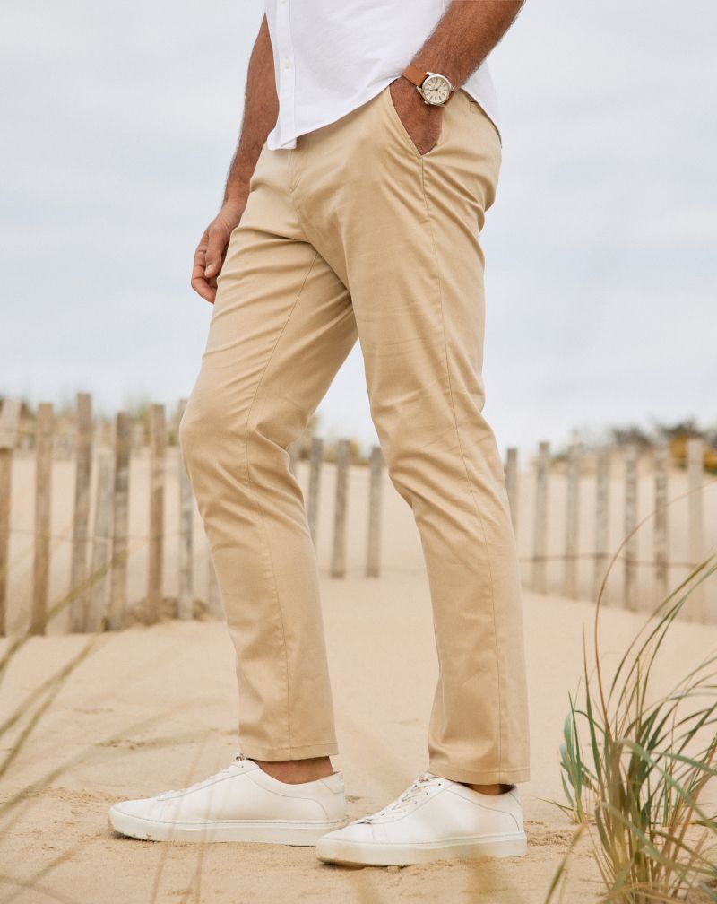 Close-up of khaki Prescott pants and white sneakers on a sandy beach path