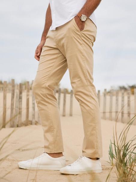 Close-up of khaki Prescott pants and white sneakers on a sandy beach path