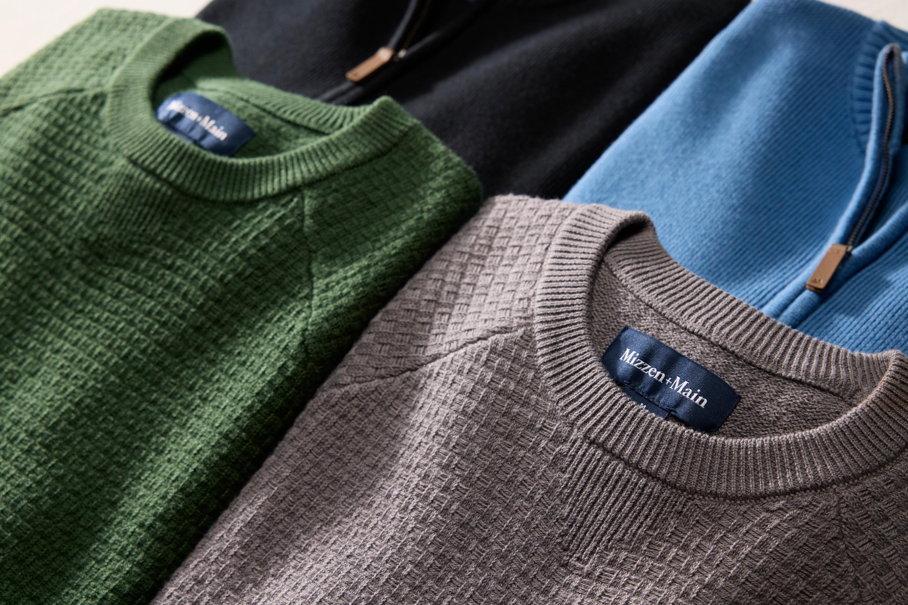 Close-up of Hillcrest sweaters in green, black, blue, and taupe with textured knit fabric