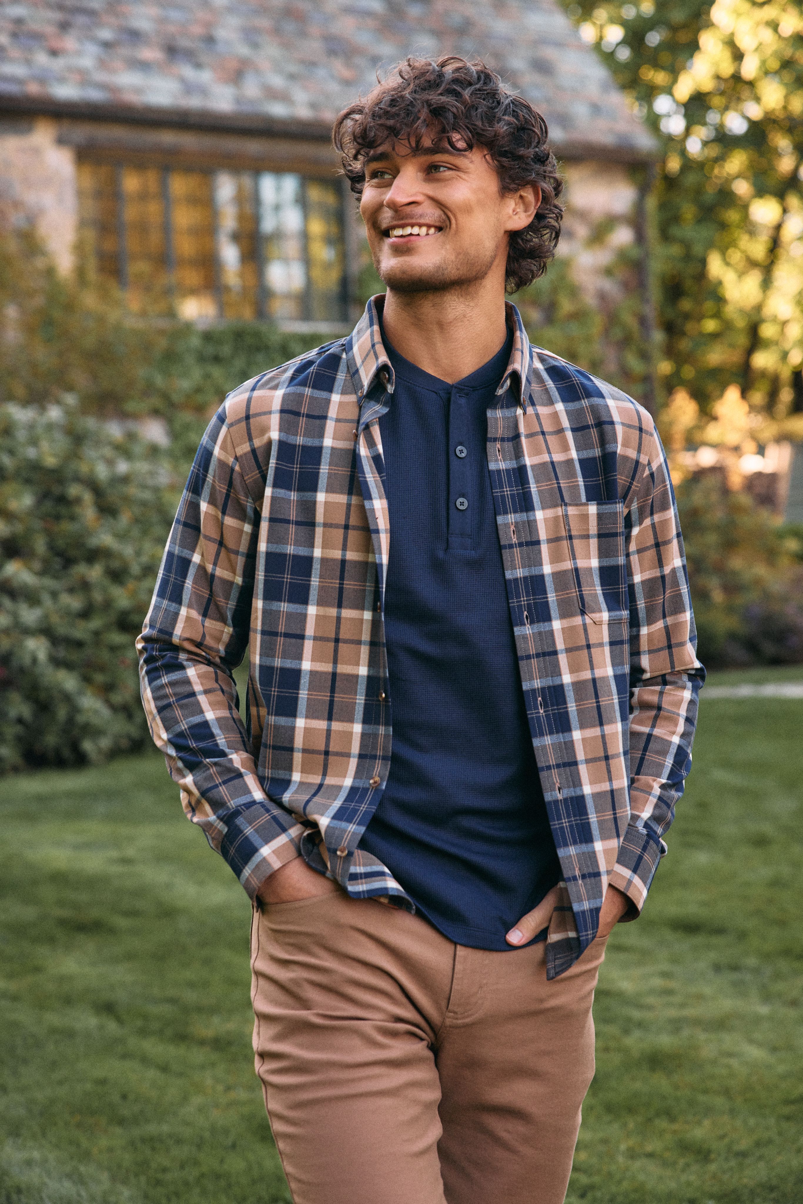 Smiling man in an open plaid flannel over a navy henley with khaki pants